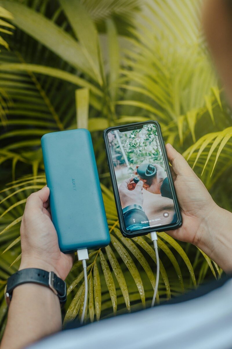 Hand holding a green portable power bank charging a smartphone, illustrating portable power banks explained