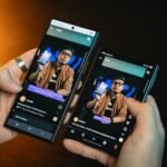 Hands holding two smartphones showing identical screens, illustrating transferring data from an old phone to a new phone